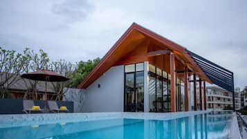 Un bâtiment moderne doté d’une piscine, caractérisé par une façade en verre et un toit en bois.