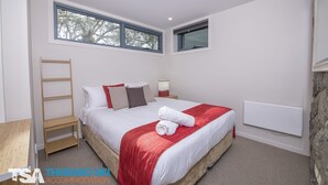 A bedroom with a bed, a nightstand, a bedside table, a ladder, and a window. - Golden Eagle 1 - Central Village (Central Village)