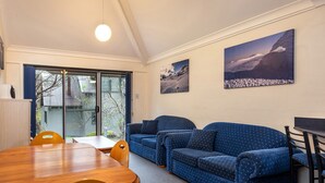 Une pièce comprenant une table à manger en bois, des canapés à motifs bleus et deux tableaux accrochés au mur.