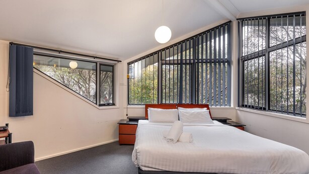 Une chambre d’hôtel avec un lit, un bureau, une chaise et un téléviseur.