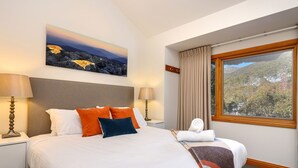 Ein Hotelzimmer mit einem großen Bett, zwei Nachttischlampen, einem Bild an der Wand und einem Fenster mit Vorhängen.