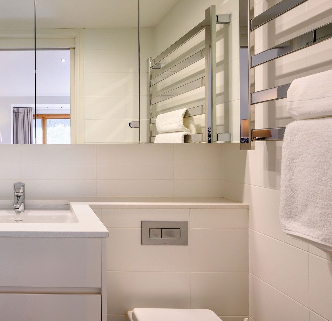 Une salle de bain moderne avec un lavabo blanc, un miroir et un porte-serviettes.