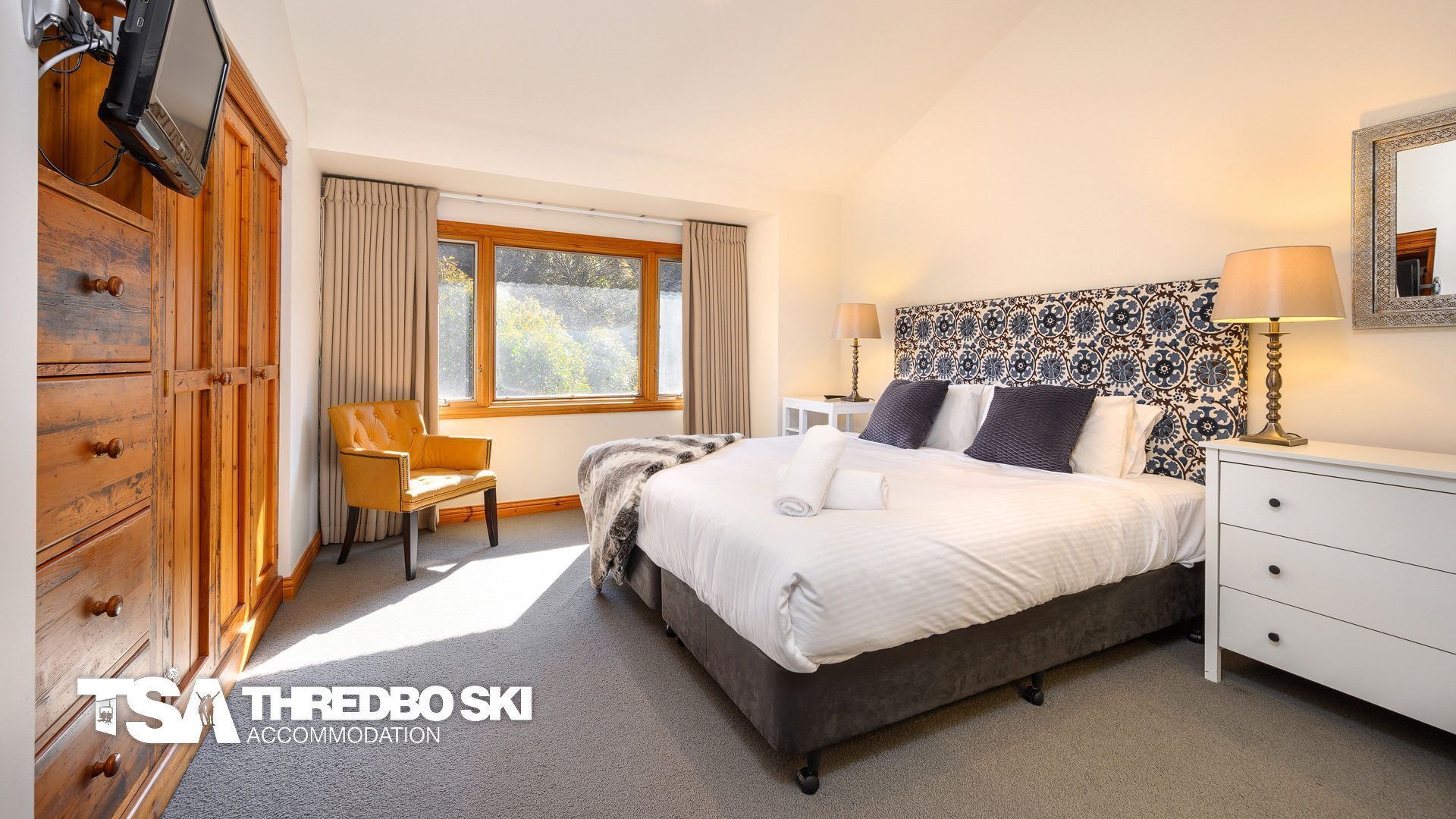 Een hotelkamer met een bed, een stoel, een bureau en een garderobe.