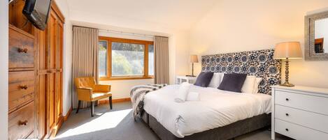Een hotelkamer met een bed, een stoel, een bureau en een garderobe.
