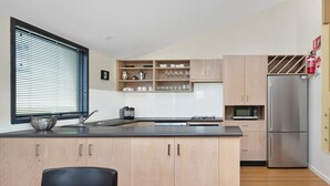 Une cuisine moderne dotée d’un îlot central, de meubles en bois et d’appareils électroménagers en acier inoxydable.