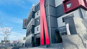 A modern building with a prominent red vertical stripe and the word "ENTRAD" on the entrance. - K Hotel (León)