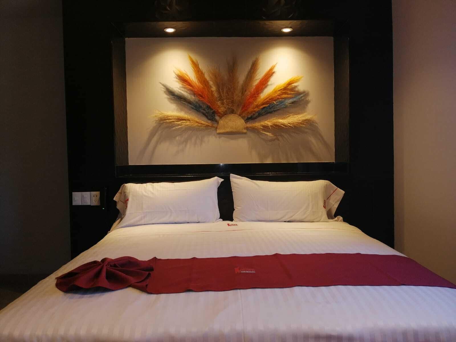 Una habitación de hotel con una cama grande, ropa de cama blanca y una manta roja.