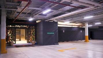A spacious indoor parking area with a circulation sign, concrete flooring, and structural columns.