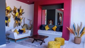 A modern living room with a white sofa, yellow ottomans, and a dark coffee table. - K Hotel (León)