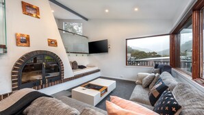 Una sala de estar moderna con chimenea, asientos cómodos, un televisor de pantalla plana y vistas al exterior.