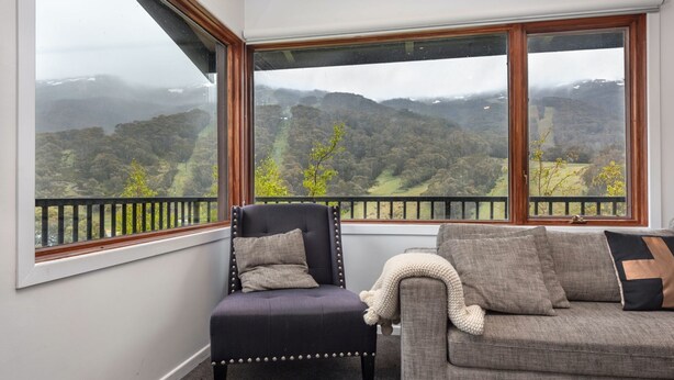 Habitación con vista a un paisaje montañoso a través de grandes ventanales.