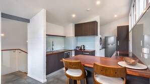 Una cocina moderna con armarios de madera oscura, un refrigerador de acero inoxidable y una mesa de comedor de madera con dos sillas.