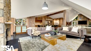 A modern living room with a large sofa, a coffee table, and a stone fireplace. - Sequoia 5 Penthouse - Central Village (Central Village)
