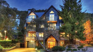 A large, multi-story house with a stone facade, a prominent front entrance, and a balcony on the upper floor. - Sequoia 5 Penthouse - Central Village (Central Village)