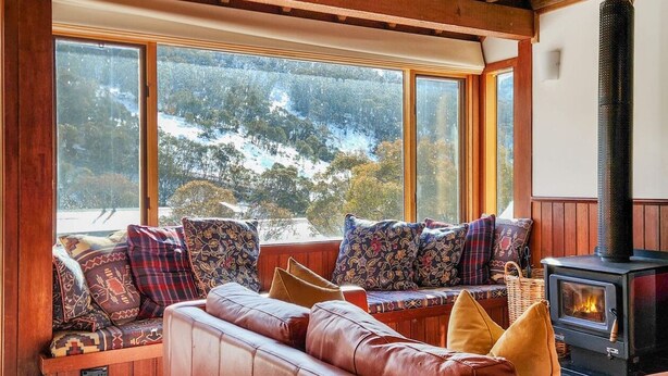 A cozy living room with a leather sofa, patterned cushions, and a wood-burning stove. - Sneznik - Central Villaage (Central Village)