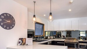 A modern kitchen with white cabinets, a built-in oven, and a large window. - Snowbound Chalet 3 - Crackenback Ridge (Crackenback Ridge)