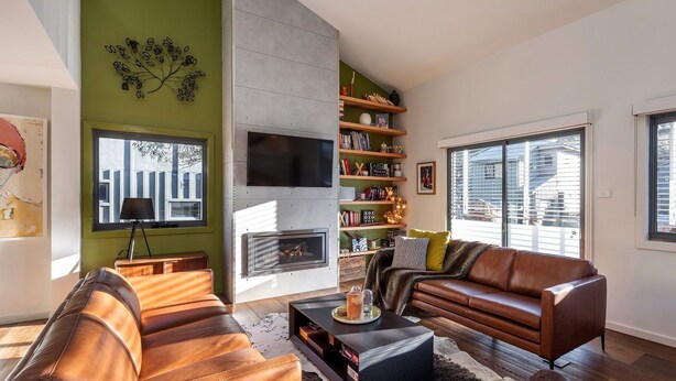 A modern living room with a fireplace, leather sofas, a coffee table, and a bookshelf.