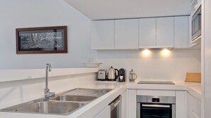 A modern kitchen with a built-in oven, a sink, and a coffee maker.