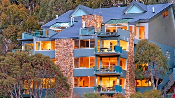 A multi-story hotel with a stone facade, balconies, and large windows.