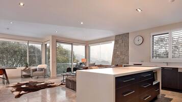 A modern kitchen with a large island, a dining area with a view, and a stone accent wall.