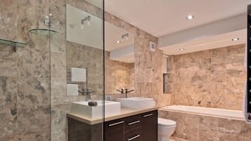 A modern bathroom with a glass shower enclosure, a double sink vanity, and a separate bathtub.