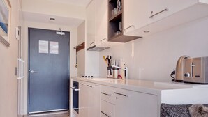 A compact kitchen with a built-in oven, a coffee machine, and a microwave. - The Peak 7 - Central Village (Central Village)