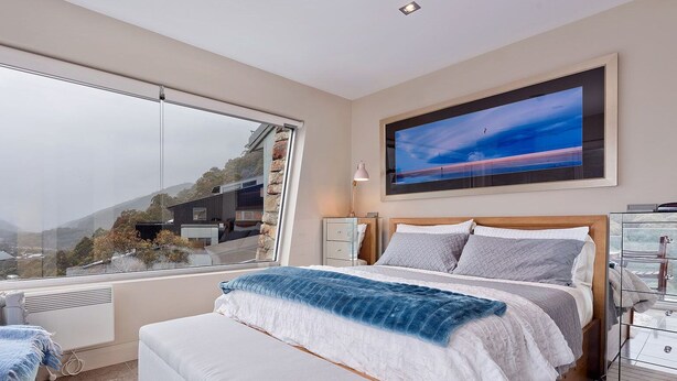 A bedroom with a large window, a bed, a chair, and a bedside table. - The Peak 7 - Central Village (Central Village)