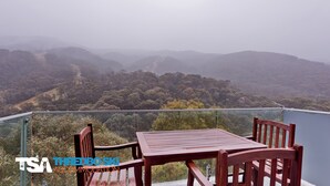 A balcony with a table and chairs overlooking a forested landscape. - The Peak 7 - Central Village (Central Village)