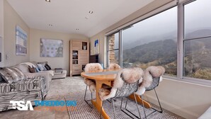 A spacious living room with a large window offering a view of the countryside. - The Peak 7 - Central Village (Central Village)