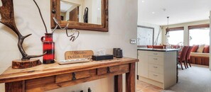 A wooden console table with a mirror, a Thredbo Default - Happy sign, and a red vase.