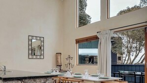 Un espace repas avec un comptoir en pierre, des chaises en bois, une table dressée pour quatre personnes et une vue sur l’extérieur.