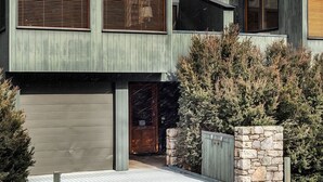 Una casa moderna de dos pisos con ventanas amplias, un garaje y un muro de piedra.
