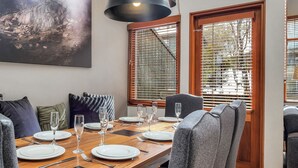 Comedor con mesa de madera dispuesta para cuatro personas, rodeado de sillas tapizadas en gris.