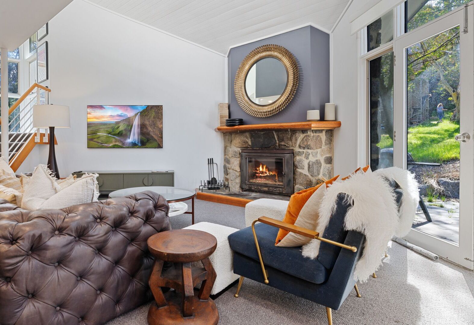 A modern living room with a fireplace, comfortable seating, and a large window offering a view of the outdoors.