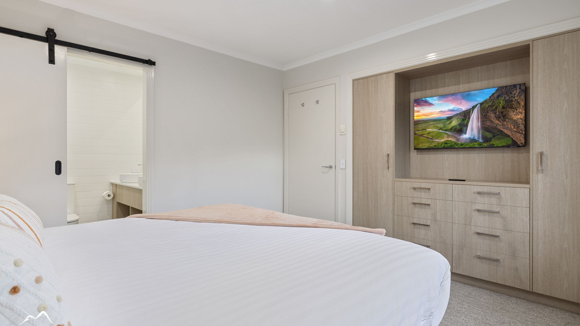 Une chambre à coucher comprenant un lit, une armoire, une télévision et une salle de bain.