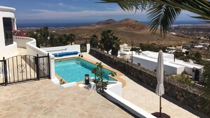 A pool with a view of the sea and hills, surrounded by white buildings and palm trees. - Private villa with stunning views and heated pool (Nazaret)