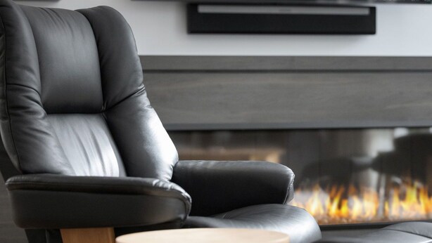 A modern living room with a leather armchair and a fireplace.