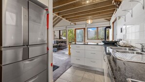 Een moderne keuken met roestvrijstalen apparatuur, witte kasten en een groot raam met uitzicht op een terras.