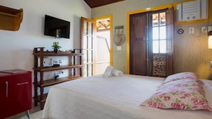 Een slaapkamer met een bed, een televisie, een houten dressoir en een raam met uitzicht.