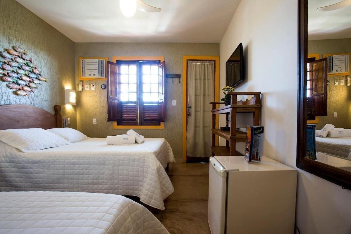 Ein Hotelzimmer mit zwei Betten, einem Fernseher, einem Kühlschrank und einem Holzboden.