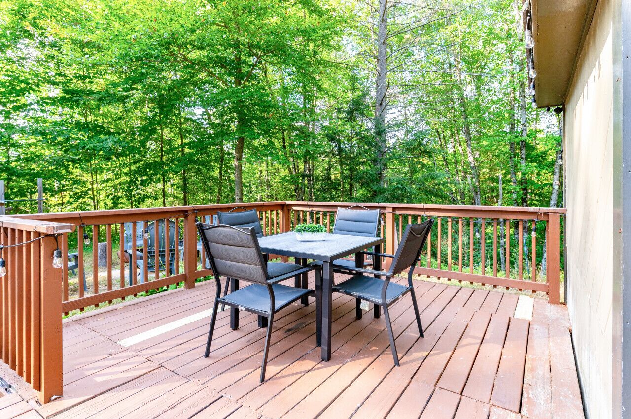 A wooden deck with a table and chairs, surrounded by a wooden railing.