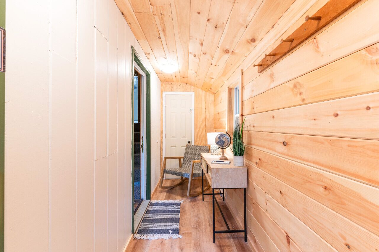 Ein Holzboden-Flur mit einer Tür, einem Stuhl, einem kleinen Tisch mit Globus und einem Blumentopf.