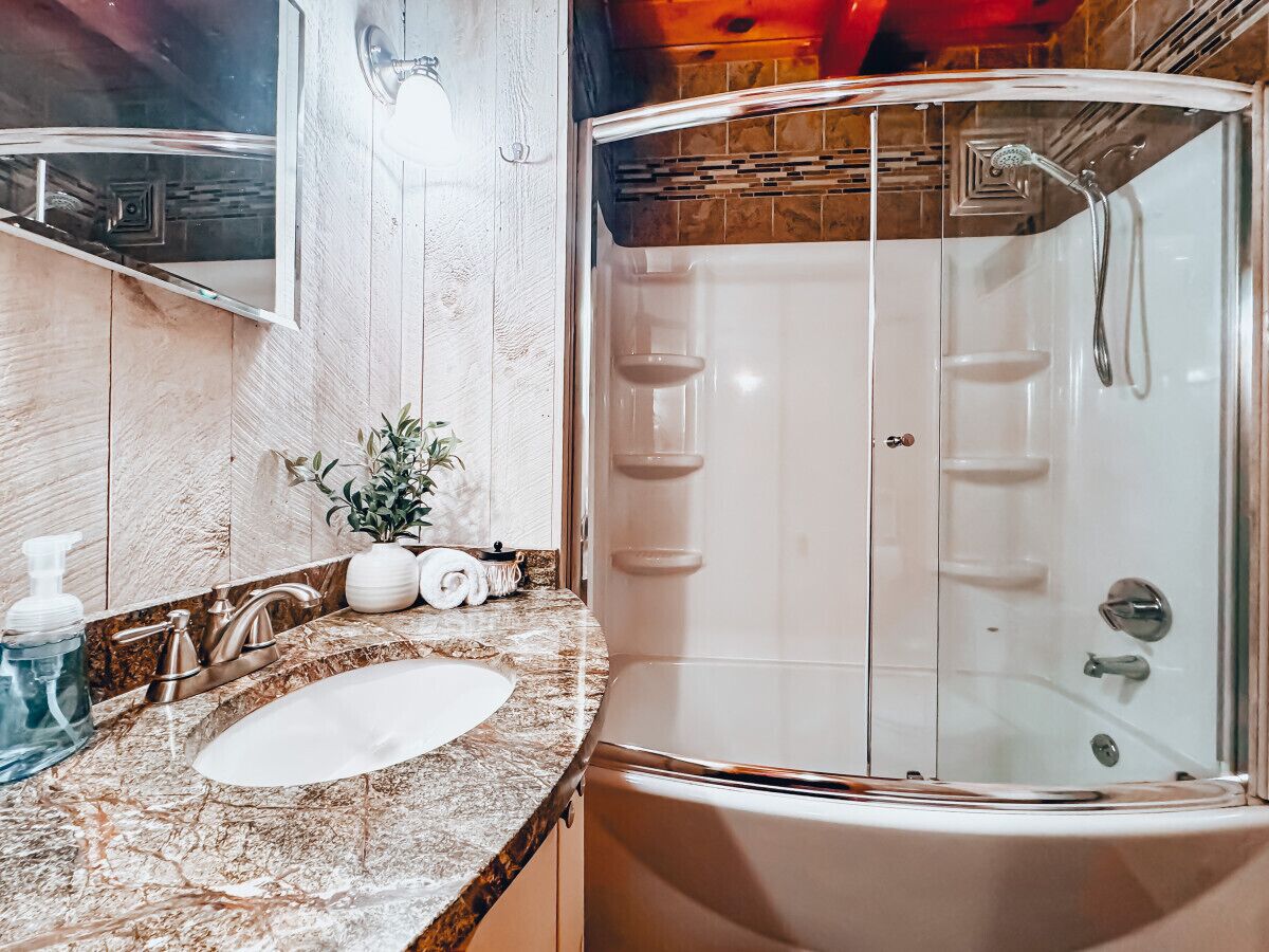 A bathroom with a marble sink, a glass-enclosed shower, and a wooden vanity.