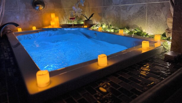 Un jacuzzi con velas alrededor, frente a una pared de azulejos.