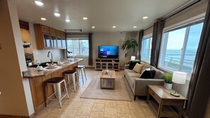 Una sala de estar moderna con zona de cocina, un ventanal con vistas y un televisor de pantalla plana.
