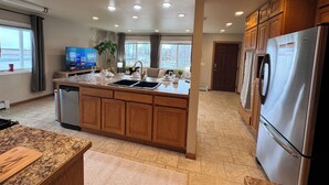 Una cocina moderna con una isla central, electrodomésticos de acero inoxidable, armarios de madera y un amplio ventanal con vistas.