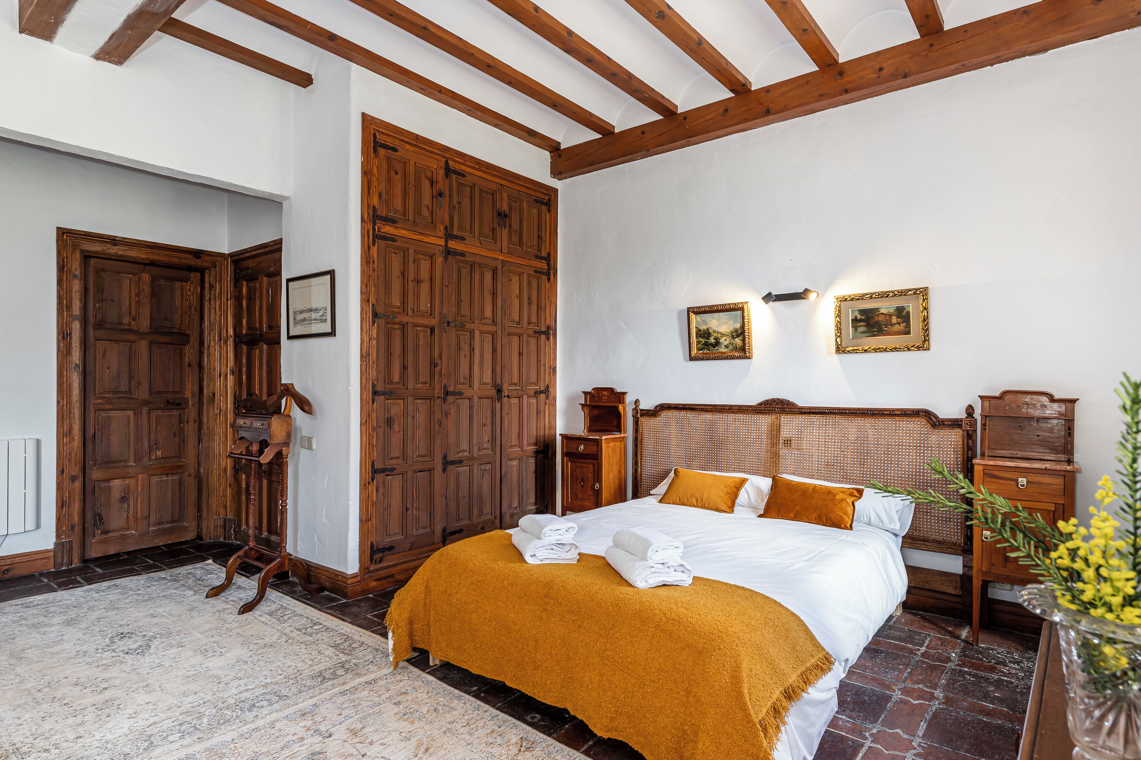 Un dormitorio con una cama grande, un armario de madera y una mesita de noche.