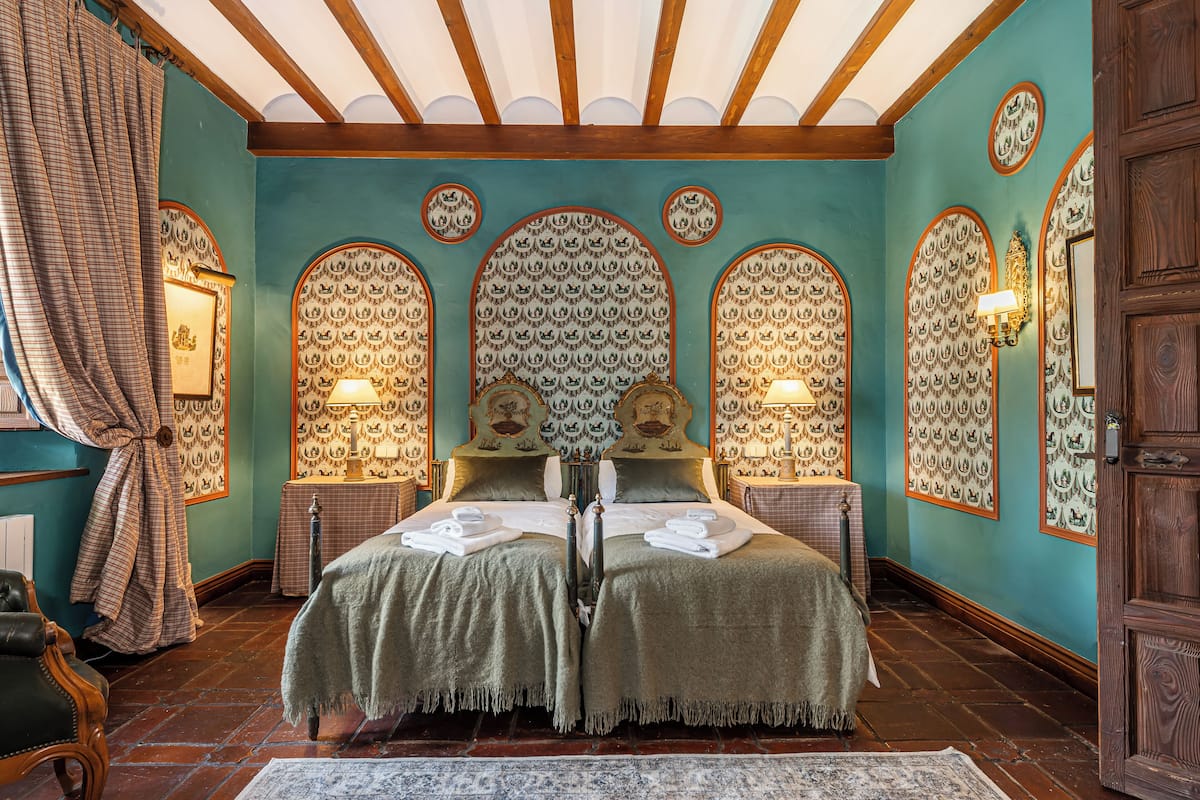 A traditional room with a bed, two bedside tables, a mirror, and a wooden door.