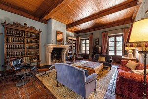 A traditional library with bookshelves, a fireplace, and classic furniture.