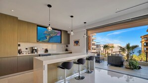 Una cucina moderna con un'isola grande, sgabelli da bar e vista sul mare.